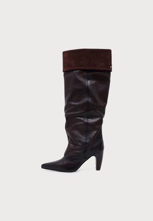 Botte en cuir marron foncé montant jusqu’au genou, avec un bout pointu, un talon bloc haut et un large revers replié.
