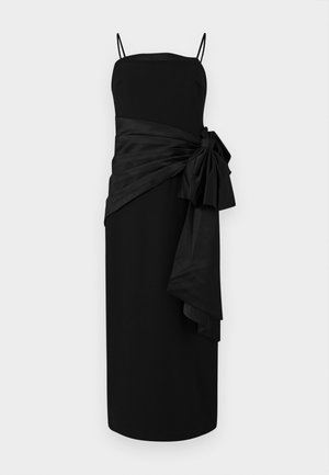 Musta mekko ohuilla olkaimilla, suora leikkaus ja drapattu satiinivyö, jossa on solmu sivulla. Sujuva rakenne ja minimalistinen muotoilu.