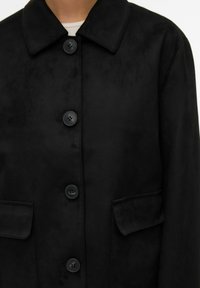 Veste en daim noire avec un col à revers, une fermeture à six boutons et deux poches avant, affichant une texture lisse et élégante.