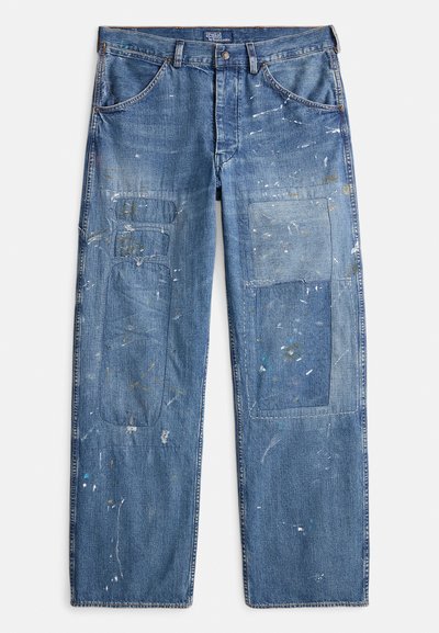 Falkede blå jeans i denim med løs passform, med flere lappet områdene og malingssprut over stoffet. Inkluderer frontlommer.