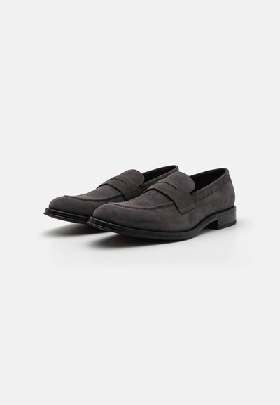 Schwarze Wildleder-Slipper mit glatter Textur, ausgestattet mit einem doppelten Riemendesign und einer niedrigen, strukturierten Gummisohle. Klassische flache Silhouette.