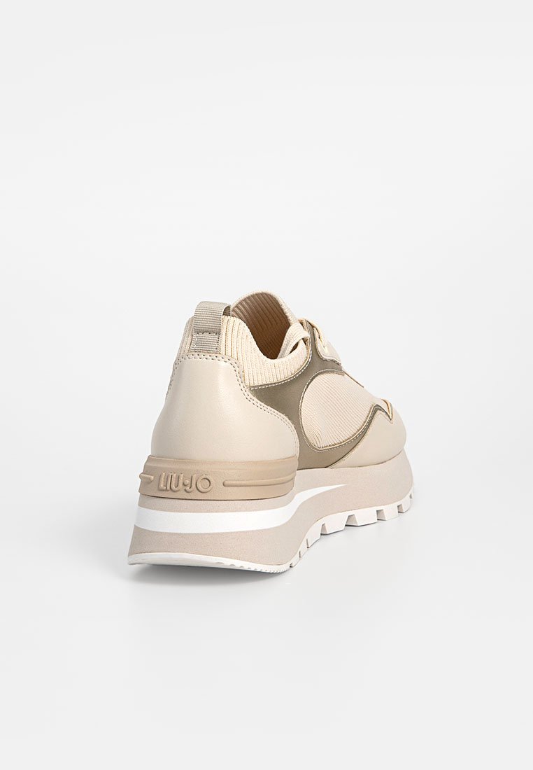 Sneaker beige con un mix di pelle e tessuto, caratterizzata da una superficie testurizzata, forma arrotondata e una suola in gomma bianca con dettaglio del logo.