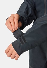 Wodoodporna kurtka w ciemnoniebieskim kolorze. Posiada regulowane mankiety na rzepy z teksturowaną powierzchnią. Gładki, elegancki design, funkcjonalna i dopasowana.