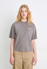 T-shirt grigia a maniche corte con vestibilità rilassata e scollatura a girocollo. Presenta il piccolo logo "Carhartt WIP" in grigio chiaro sul petto.