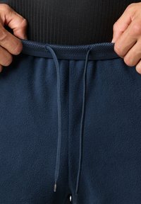 Navyblauwe fleecebroek met een gestructureerd oppervlak, voorzien van een tailleband met een trekkoord en een gladde elastische band.