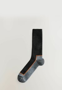 Sort ribbet strømpe med kontrasterende grå hæl og tå, der har en orange accentstribe langs sømmen. Blød stoffets tekstur.