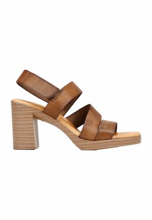 Sandalias de tacón de piel marrón con tres correas anchas, punta abierta y un tacón cuadrado. Presenta un patrón de grano de madera clara en el tacón.