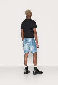 Μαύρη μπλούζα κοντό μανίκι, συνδυασμένη με ανοιχτό μπλε τζιν σορτς. Τα σορτς έχουν ξεθωριασμένο look και πίσω τσέπες, ολοκληρωμένα με μαύρες μπότες.