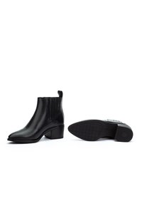 Par de botas de tobillo de cuero negro con tacones cuadrado, paneles laterales elásticos y una lengüeta, mostradas desde un lado y desde la vista de la suela.