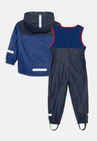 Marineblaue Regenjacke mit reflektierenden Akzenten und elastischen Bündchen; passende Hose mit roten und blauen Akzenten, ausgestattet mit elastischem Bund und Stiefelriemen.