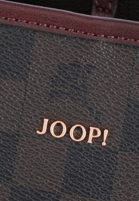 Brun mønstret pung lavet af struktureret materiale med en bourgognefarvet kant. Har en gylden "JOOP!"-logo og et gitterdesign.