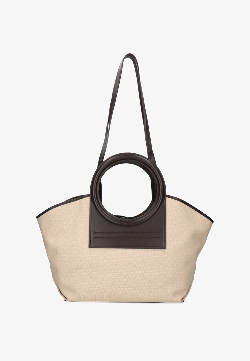 Bolsa de tela beige con asa circular marrón oscuro y correa para el hombro a juego, parche rectangular de cuero en el centro del frente.