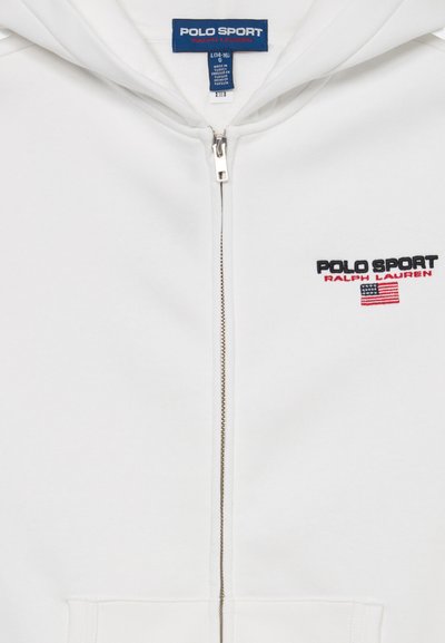Bijela zip-up dukserica s kapuljačom, na kojoj su crnim i crvenim vezom ispisani "POLO SPORT" i "RALPH LAUREN", te mala američka zastava.