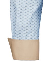 Geknöpfter Hemdsärmel aus einem hellblauen Stoff mit einem Fächerdesign in dunklerem Blau. Der Bund ist einfarbig beige.