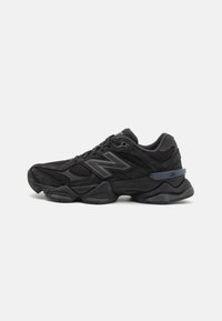 Black athletic shoe featuring a mesh and suede upper, prominent cushioning sole, textured accents, and reflective logo detail.