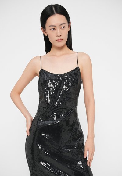 Čierne šaty so flitrami s priliehavým strihom, tenkými ramienkami a hladkou textúrou. Flitre odrážajú svetlo a vytvárajú trblietavý efekt.