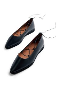 Ballet flats in pelle nera con punta affusolata e dettagli in pizzo incrociato sulla parte superiore. Suola piatta e texture liscia.