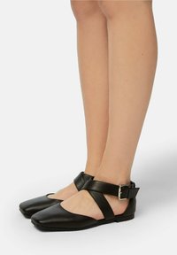 Balerini din piele neagră, cu vârf pătrat, având un design cu barete încrucișate și o cataramă ajustabilă la gleznă. Toc plat.