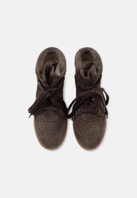 Ζευγάρι καφέ δερμάτινα sneakers υψηλού κορμού με διάτρητες λεπτομέρειες και χοντρά κορδόνια δεμένα χαλαρά, σε λευκό φόντο, φωτογραφημένα από πάνω.