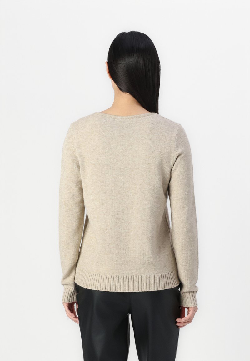 Pull en tricot beige avec des manches longues et un col rond. Présente des poignets et un ourlet côtelés, fabriqué en mélange de laine doux. Vue de dos.