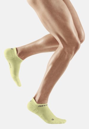 Gelbe Sportsocken mit niedrigem Schnitt, die mit strukturierten Mustern und einem engen Sitz um den Knöchel versehen sind.