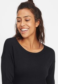 Maglione nero lavorato a maglia con scollatura ampia, maniche lunghe e bordi a costine. Texture morbida e vestibilità rilassata.