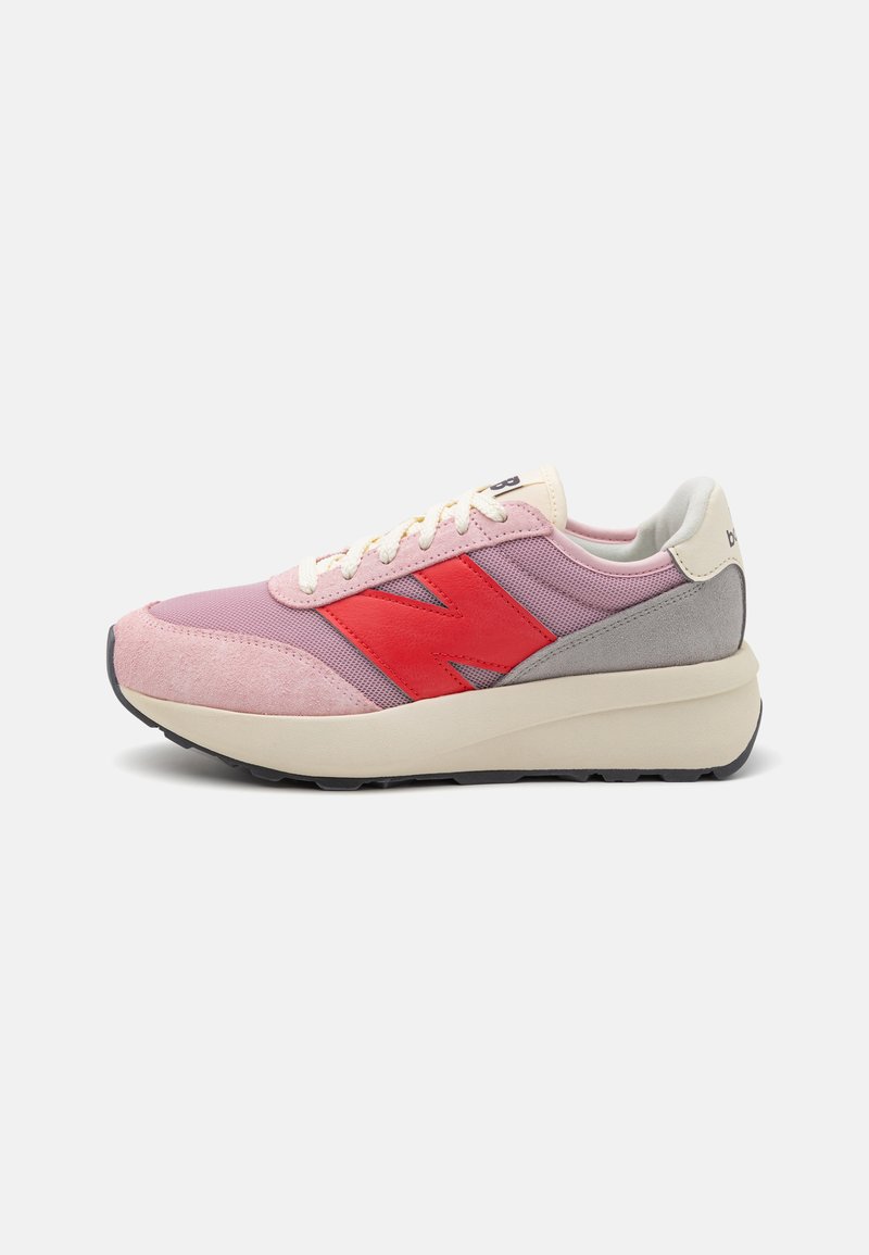 Light pink sneakers with red and gray accents, textured mesh and suede materials, featuring a rounded toe and a thick elasticized sole.