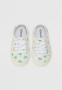 Kanga-sneakerid valge alusega, millel on rohelised palmipuude mustrid ja oranžid aksessuaared, mida täiendavad valged lipsud ja kummist talla.