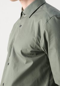 Olijfgroene overhemdd met een gestructureerde kraag, met een gladde textuur en contrasterende donkere knopen, tailored fit.