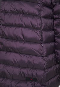 Veste matelassée violette avec des sections quiltées horizontales, texture en nylon lisse et une poche zippée sur le côté. Logo de la marque présent.