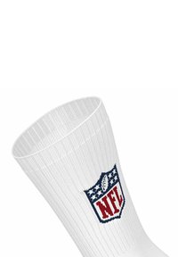 Vit atletisk strumpa med ribbad textur, med en broderad blå och röd NFL-logotyp högst upp, som visar stjärnor och en fotbollsdesign.