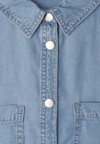 Chemise en denim bleu clair devant avec col, trois boutons-pression argentés, coutures doubles et deux poches avant partielles visibles.
