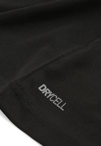 Tela atlética negra con una superficie texturizada, con el logo "DRYCELL" en gris en un lado, enfatizando las propiedades de absorción de humedad.