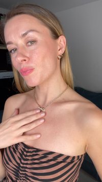 Guld kædede halskæde med rund vedhæng, parret med guld hoops øreringe, båret på bar skulder, iført en stribet top i brun og sort.