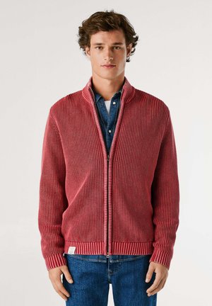 Cardigan a coste rossa con chiusura a zip e colletto, abbinato a una camicia di jeans. Tessuto testurizzato e coste a contrasto nei polsini e nell'orlo.