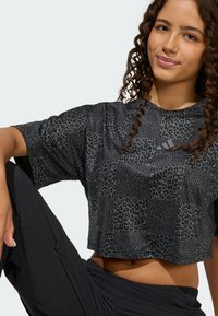 Czarny krótki t-shirt z wzorem w cętki lamparta, krótkimi rękawami i okrągłym dekoltem. Na przodzie znajduje się subtelne logo.