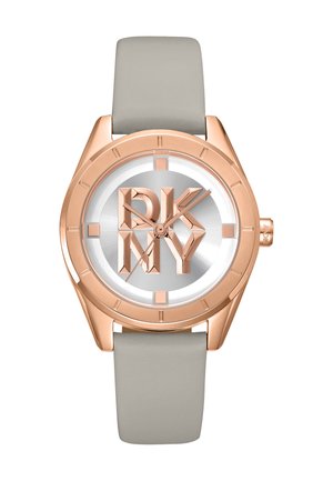 Montre en or rose avec un cadran argenté arborant le logo "DKNY" en lettres audacieuses, un bracelet en silicone gris et des marqueurs horaires minimalistes.