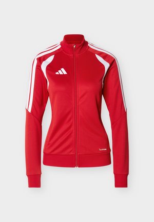 Veste zippée rouge en matériau lisse, avec des accents blancs, trois bandes blanches sur les manches et un petit logo sur la poitrine.