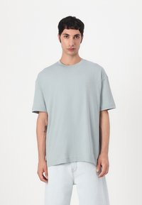 T-shirt oversized vert clair en coton. Présente un col rond et des manches courtes. Logo subtil imprimé dans une teinte plus claire sur la poitrine.