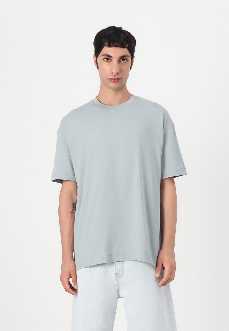 T-shirt oversized vert clair en coton. Présente un col rond et des manches courtes. Logo subtil imprimé dans une teinte plus claire sur la poitrine.
