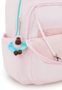 Růžový batoh s světle modrým zipem a klíčenkou v podobě chlupaté opice s hnědou tváří a modro-růžovými akcenty.