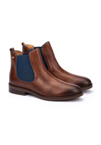 Pair of brown leather Chelsea boots with dark blue elastic side panels and low stacked heels on white background.