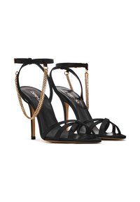 Zwarte hoge hakken sandalen van soepel leer met gekruiste banden, enkelkettingdetail en slanke stiletto-hakken.