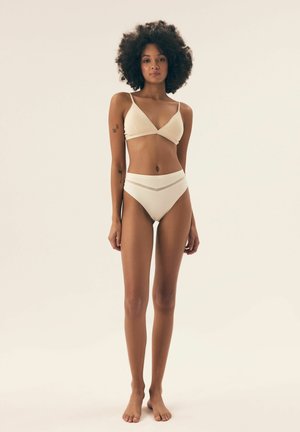 Zweiteiliges Bikini-Set in Off-White. Der Bralette hat dünne Träger und eine dreieckige Form. Die hochgeschnittenen Unterteile haben ein kontrastierendes Band.