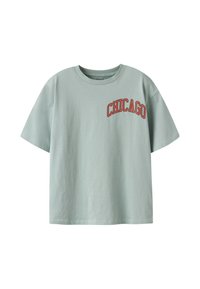 T-shirt vert clair à manches courtes avec un graphique rouge "CHICAGO" sur la partie supérieure gauche de la poitrine. Fabriqué en coton, avec une coupe décontractée.