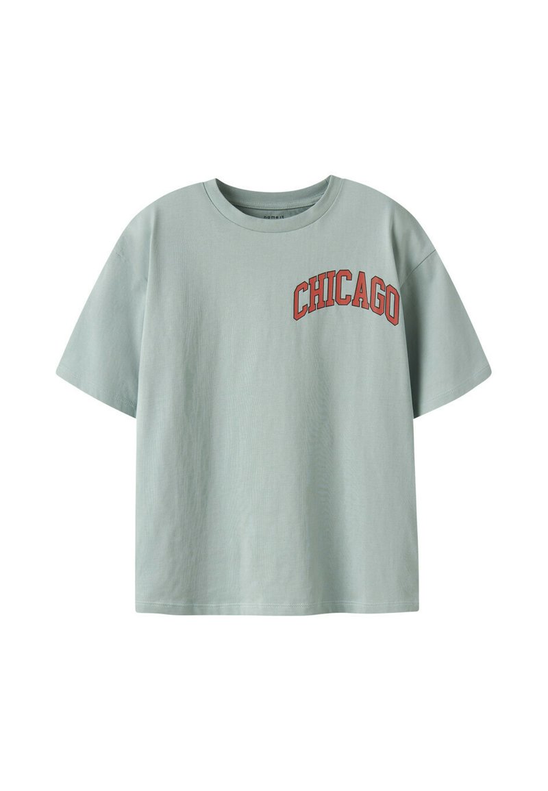 T-shirt vert clair à manches courtes avec un graphique rouge "CHICAGO" sur la partie supérieure gauche de la poitrine. Fabriqué en coton, avec une coupe décontractée.