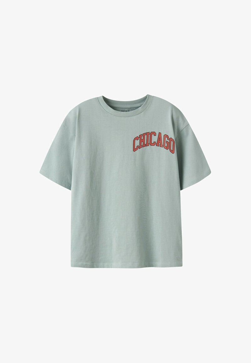 T-shirt vert clair à manches courtes avec un graphique rouge "CHICAGO" sur la partie supérieure gauche de la poitrine. Fabriqué en coton, avec une coupe décontractée.