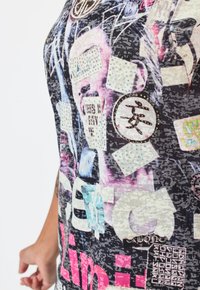 Zwarte graphic t-shirt met kleurrijke prints, verschillende stickers en rhinestones, met een mix van tekst en afbeeldingen door het hele ontwerp.