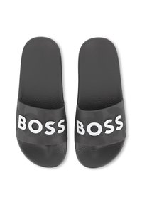 Svarte slidesandaler med en strukturert stropp med "BOSS"-logo i hvitt. Sålen har en grusete overflate for bedre grep.