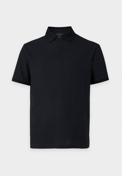 Polo manches courtes noir avec un motif texturé, un col et une patte de boutonnage sur un fond gris clair.